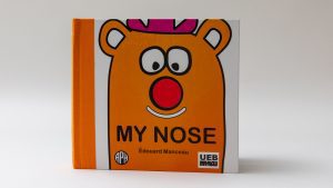My Nose front cover on a white background. The main character is orange with a pink hat and a red nose. The book says 